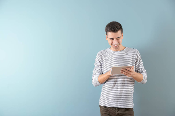 Young man using tablet computer on color background - Foto, Imagen
