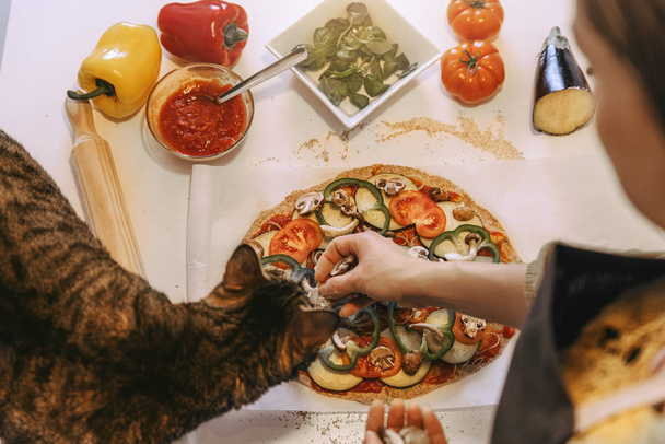Mujer preparando deliciosa pizza con su dulce gato
. - Foto, Imagen