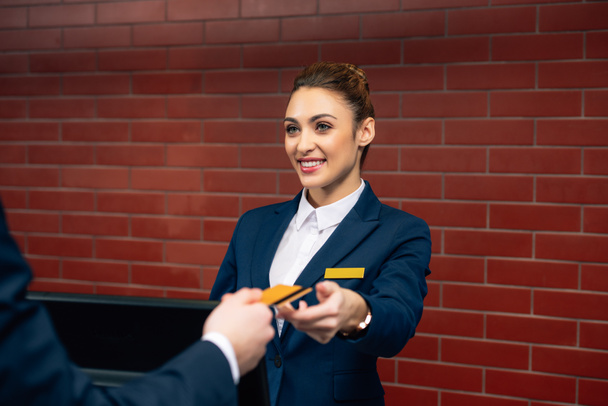 young beautiful hotel receptionist taking credit card from customer - Photo, Image
