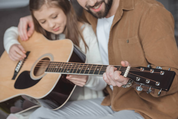 cropped image of father teaching daughter playing acoustic guitar - Photo, Image