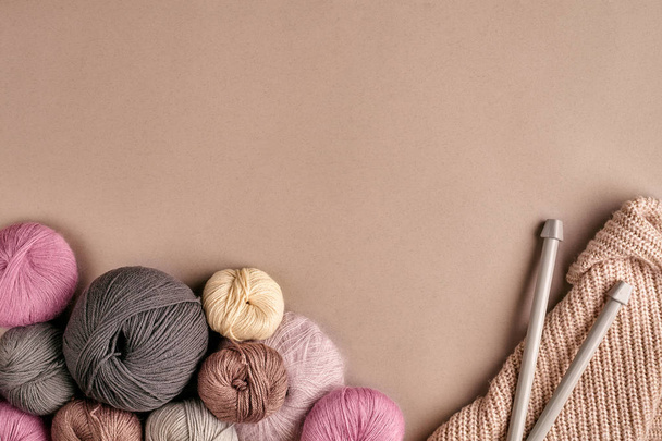 A group of colored balls of yarn and knitting needles on a beige background - Photo, Image