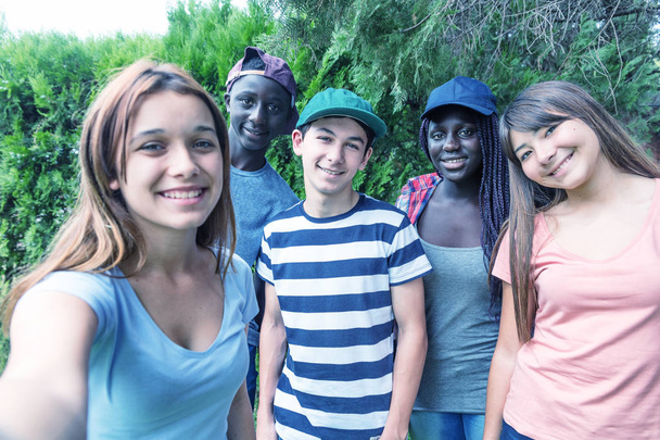 Groupe d'adolescents multi-ethniques en plein air faisant selfies
. - Photo, image