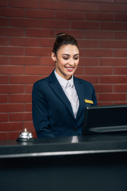 young beautiful hotel receptionist looking at computer screen at workplace - Photo, Image