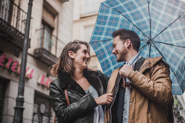 Para zakochanych na ulicy w deszczowy dzień. Przyjaciele idąc ulicą - Zdjęcie, obraz