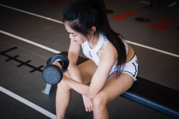 Young woman lifting dumbbell in gym. - Foto, imagen