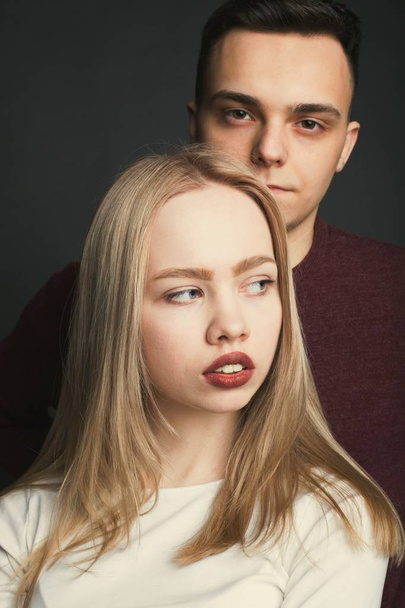 Portrait of a beautiful young couple in love posing at studio over dark background - Photo, Image