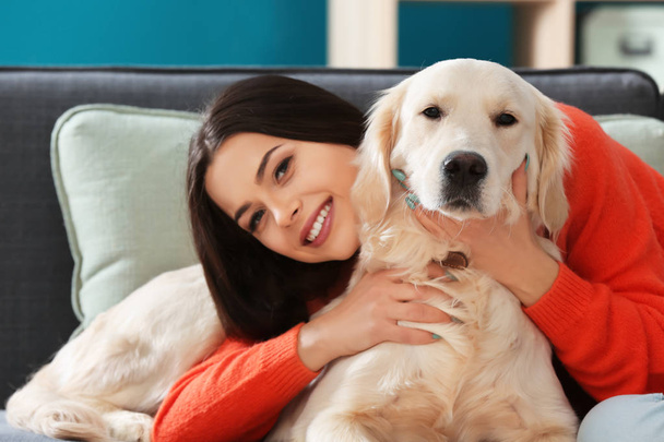 Young woman with dog indoors. Friendship between pet and owner - Photo, image