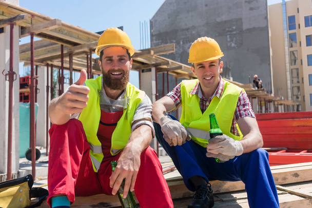 Двоє молодих працівників п'ють холодне пиво під час перерви на роботі
 - Фото, зображення