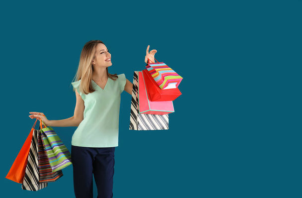 Happy young woman with shopping bags on color background - Photo, Image