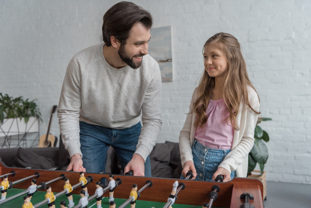 father and daughter playing table football at home - Фото, зображення
