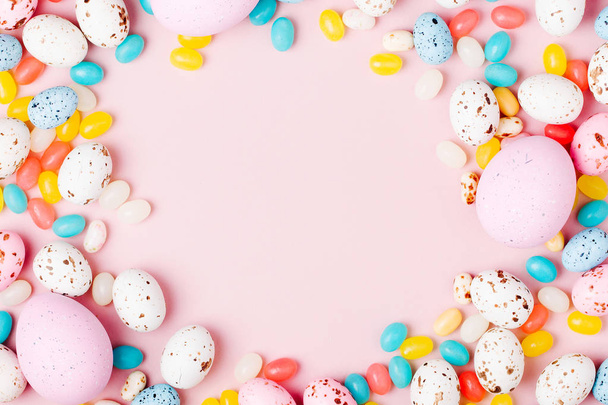 Stylish frame made of Easter candy chocolate eggs and Jellybeans on pink background - Φωτογραφία, εικόνα