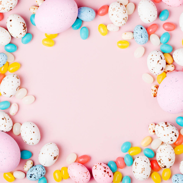Stylish frame made of Easter candy chocolate eggs and Jellybeans on pink background - Photo, image