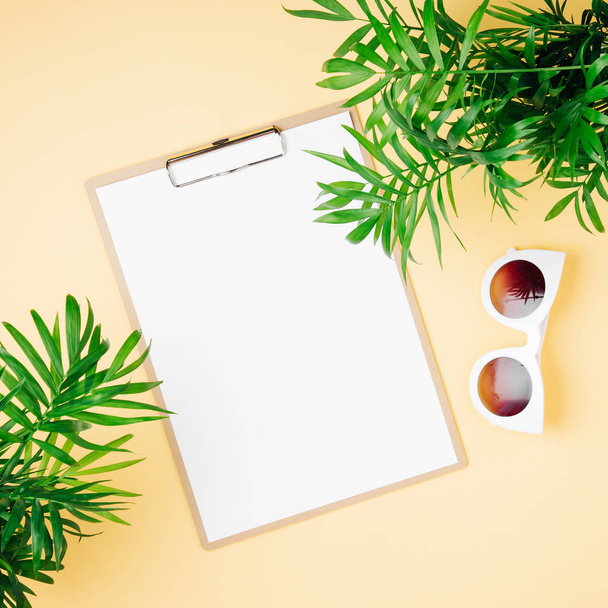 Tropical leaves, clipboard mockup with sunglasses  on  yellow  background. Top view, flat lay. - Foto, Imagen