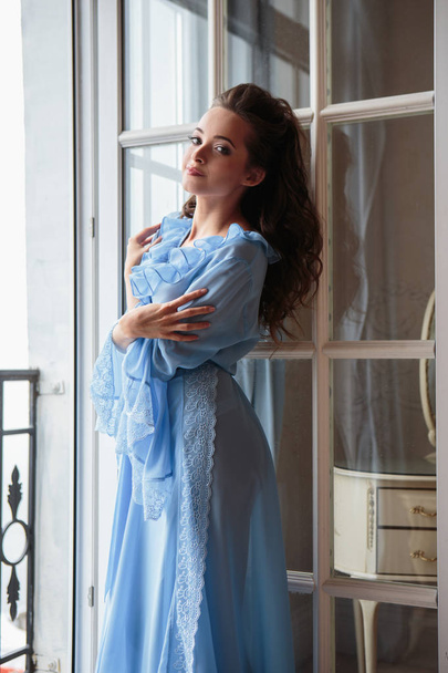 Beautiful bride young woman in a blue long peignoir in a wedding morning - Fotografie, Obrázek