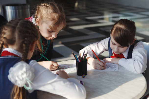Schoolchildren draw with colored pencils sitting at the table - Photo, Image