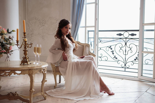 Beautiful bride in a white wedding peignoir in a morning. beauty portrait in interior - Fotografie, Obrázek