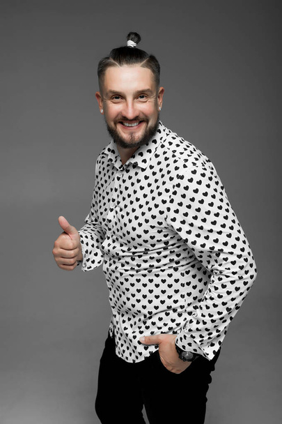 συναισθηματική άνθρωπος σε ένα πουκάμισο με μαύρες καρδιές σε ένα γκρίζο φόντο - Φωτογραφία, εικόνα