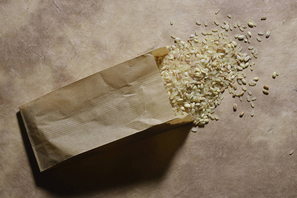 Pieni pussi ruokakaupan paperia ohralla ja tavatuilla riisinjyvillä
 - Valokuva, kuva