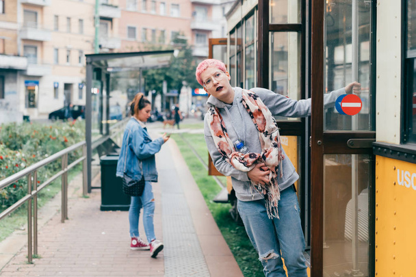 jonge vrouw roze haar buiten krijgen van de tram - vervoer, woon-werkverkeer, reiziger concept - Foto, afbeelding