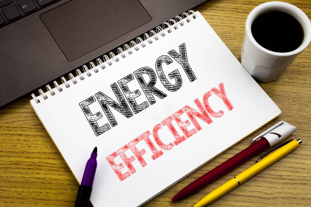 Scrivere un testo che mostri l'efficienza energetica. Business concept per l'Ecologia Elettrica scritto sul taccuino sullo sfondo in legno dell'Ufficio con laptop
 - Foto, immagini