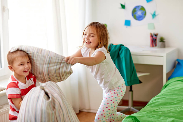 kids playing and fighting by pillows at home - Foto, Imagem