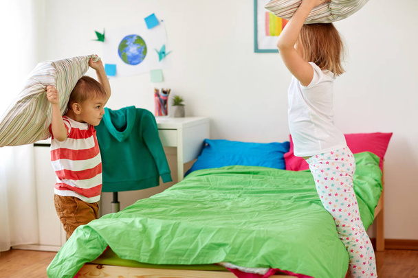 kids playing and fighting by pillows at home - Foto, immagini
