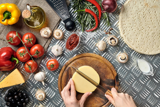 osittainen näkymä nainen leikkaa juustoa kypsennyksen aikana kotitekoinen italialainen pizza
 - Valokuva, kuva