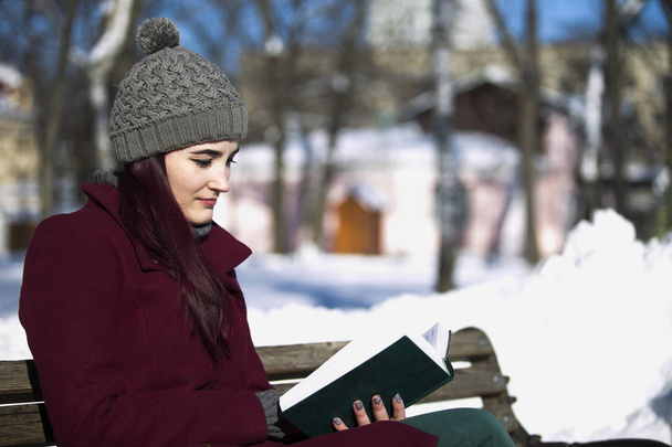 hermosa chica en sombrero y chaqueta leyendo un libro, sentado en una b
 - Foto, imagen