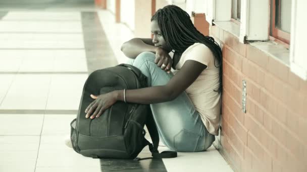 School bullying. Afro american female teenager upset seated in school hallway. - Footage, Video