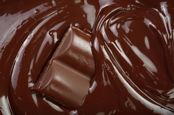 Rozpuštěnou čokoládou a kousky čokolády jako pozadí closeup - Fotografie, Obrázek