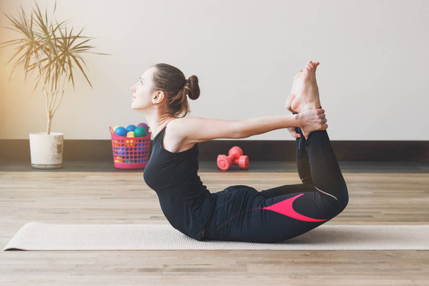 Woman makes the yoga exercise on the mat, indoors - Fotografie, Obrázek