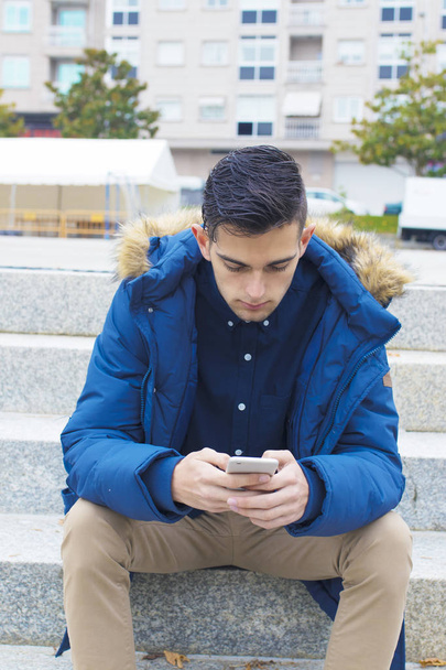 молодий дорослий з мобільним телефоном на сходах міста
 - Фото, зображення
