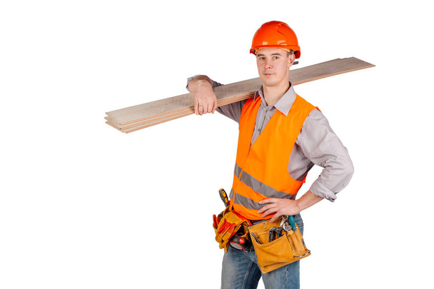 builder in a helmet holding floorboards and looking at camera over white wall background. repair, construction, building, people and maintenance concept. - Photo, Image