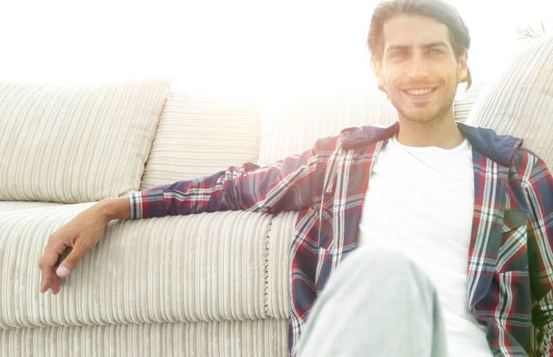 confident guy sitting on the carpet in a cozy living room. - Fotó, kép