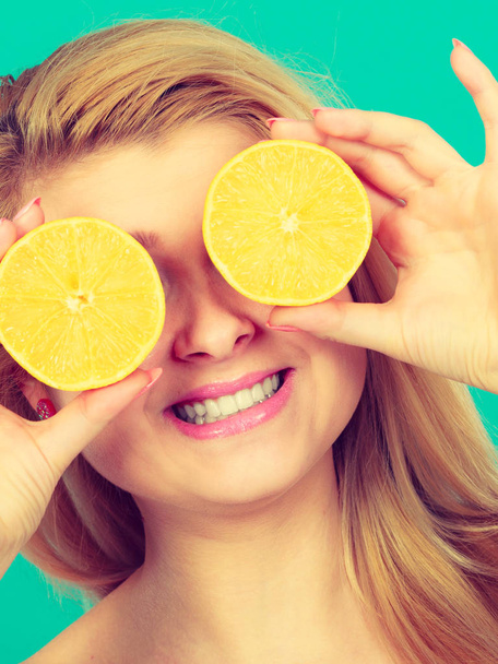 Girl covering her eyes with lemon citrus fruit - Valokuva, kuva