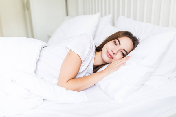 Nő alszik az ágyában. Gyönyörű fiatal nő mosolyogva alszik az ágyban - Fotó, kép