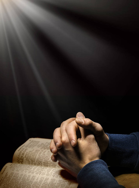 Kädet ristissä rukouksessa Raamatun yllä
 - Valokuva, kuva