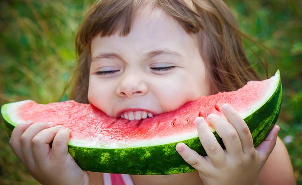 Een kind eet watermeloen. Selectieve aandacht. - Foto, afbeelding