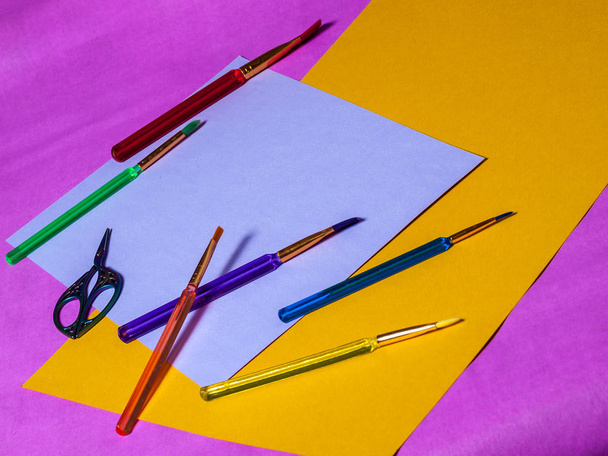 Pinceles y tijeras multicolores sobre un fondo multicolor
 - Foto, imagen