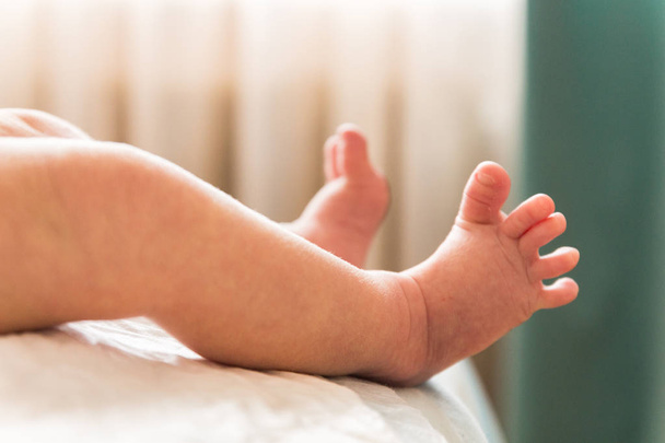 Twee kleine benen van een baby. Onscherpe achtergrond. - Foto, afbeelding