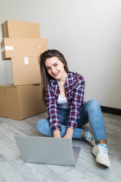 Jonge vrouw verhuizen naar een nieuwe woning zitten op de vloer in appartement leeg en bereken huis budget. - Foto, afbeelding