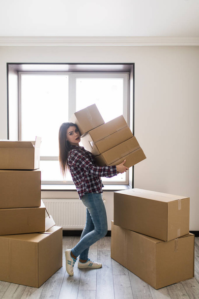 Счастливая улыбающаяся женщина с картонными коробками переезжает в новую квартиру
 - Фото, изображение