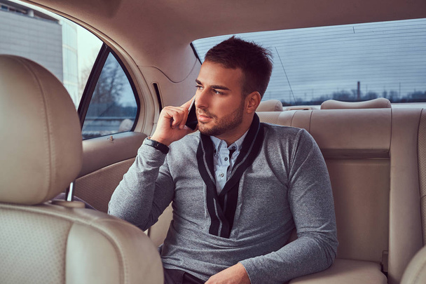 Pohledný podnikatel v elegantní oblečení pracovní, mluvil po telefonu při sezení v autě. - Fotografie, Obrázek