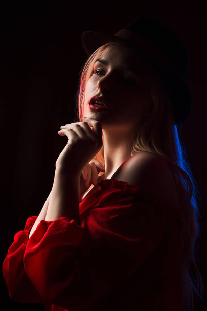 Милая молодая женщина в красной блузке и шляпе, позирующая в шаде
 - Фото, изображение