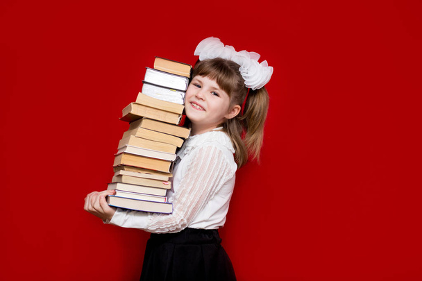 Portrait of cheerful little girl isolated on red hold many books. Concept of knowledge or school. Book lover. - Photo, Image