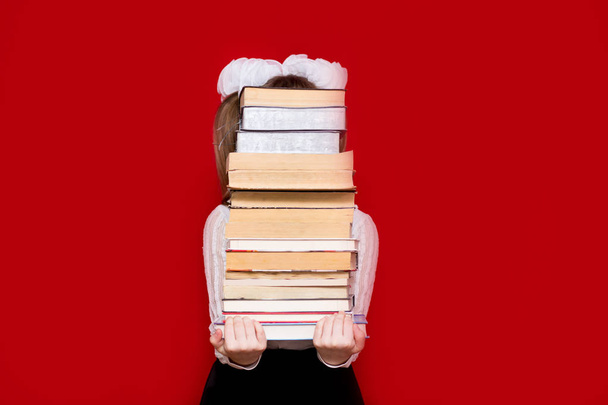 Neşeli küçük kız portresi kırmızı beklemeye pek çok kitap izole. Bilgi ya da okul kavramı. Kitap sevgilisi. - Fotoğraf, Görsel