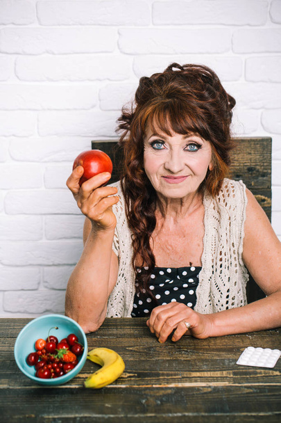 Elderly woman smile with apple in hand - Fotó, kép