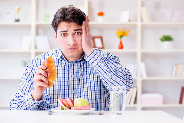 Mann in Diätfalle zwischen gesunder Ernährung und Brot - Foto, Bild