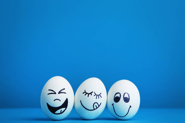 Eggs with funny faces on blue background - Foto, Bild