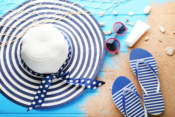 Beach hat with sunglasses and flip flops on wooden table - Фото, зображення